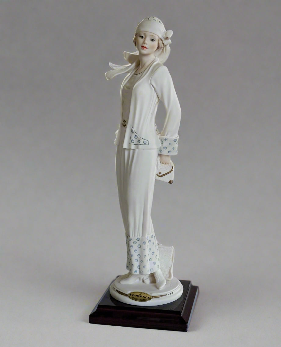 White ceramic figurine of a woman on a wooden base against a white background