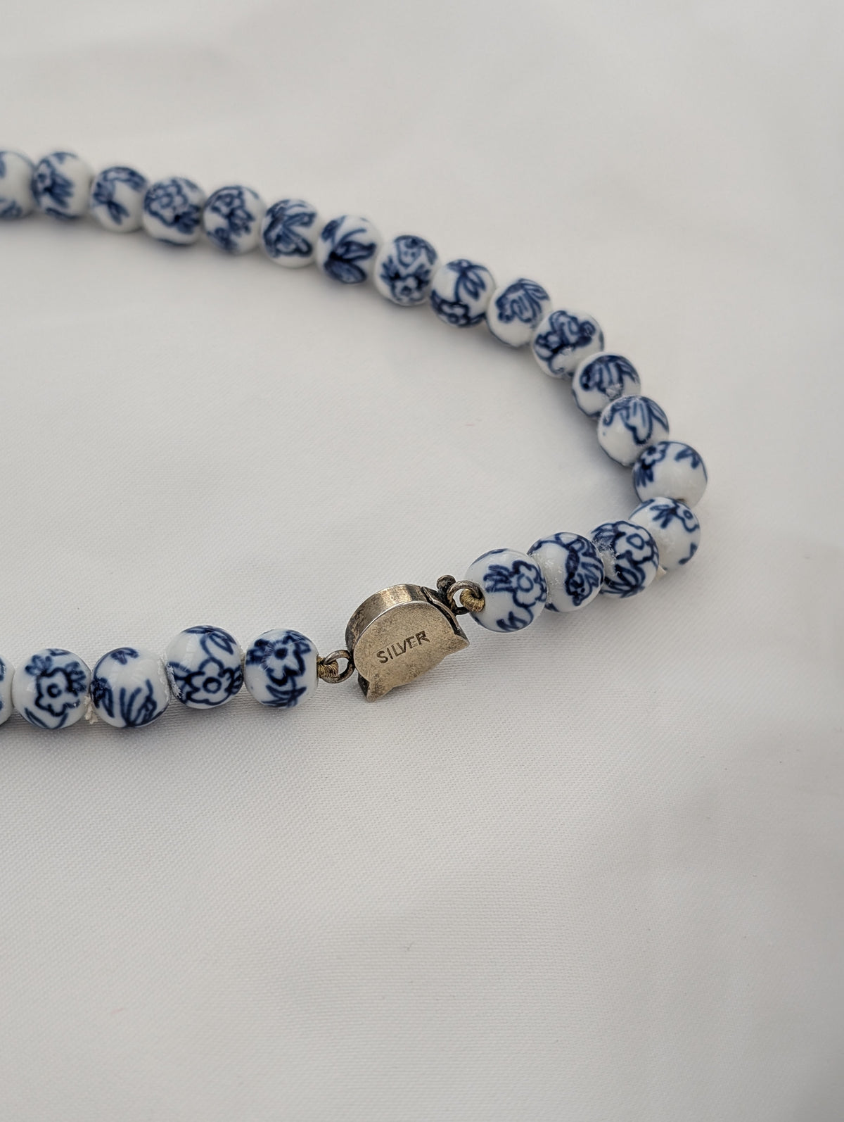A Long Strand of Chinese Porcelain Beads with a Silver Cat Clasp, c1970's
