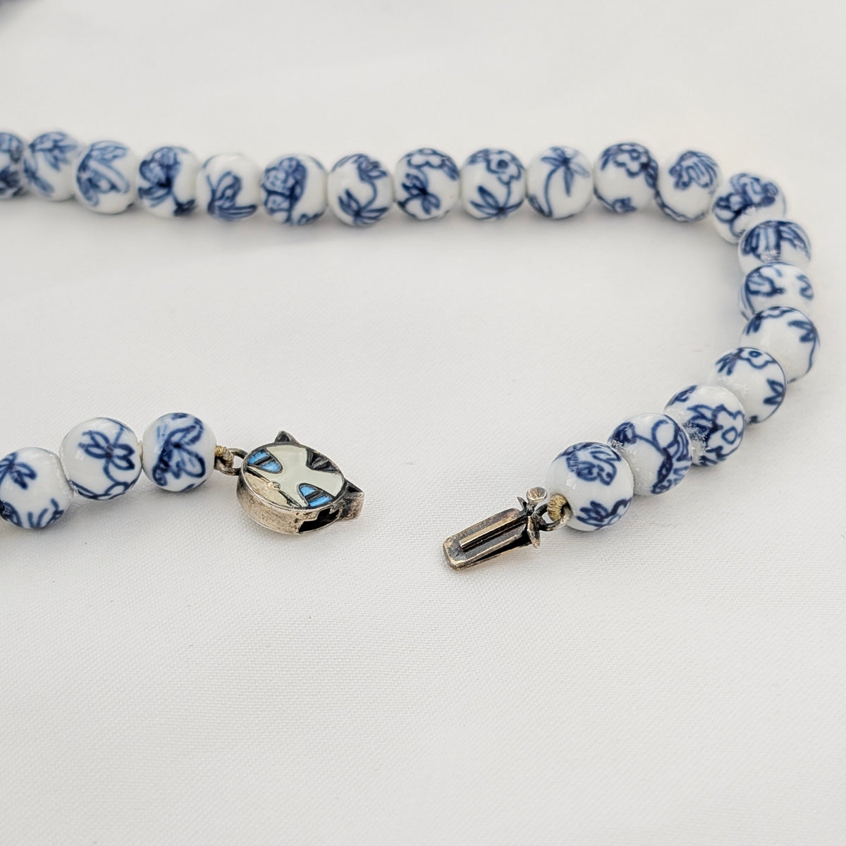 A Long Strand of Chinese Porcelain Beads with a Silver Cat Clasp, c1970's