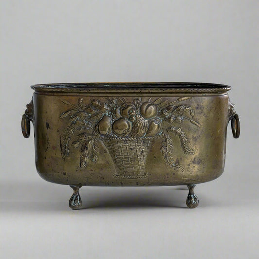 Bronze planter with decorative fruit basket design on a white surface