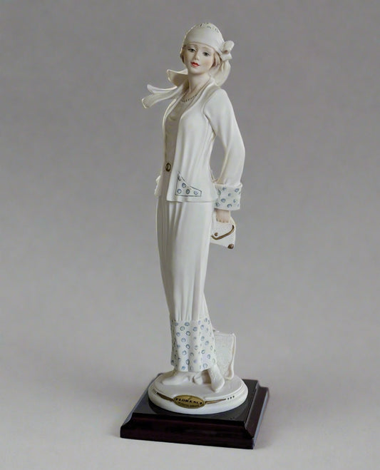 White ceramic figurine of a woman on a wooden base against a white background
